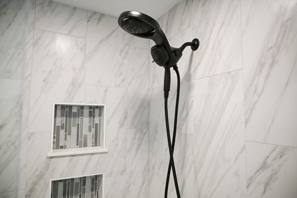 black shower head in marble tile shower